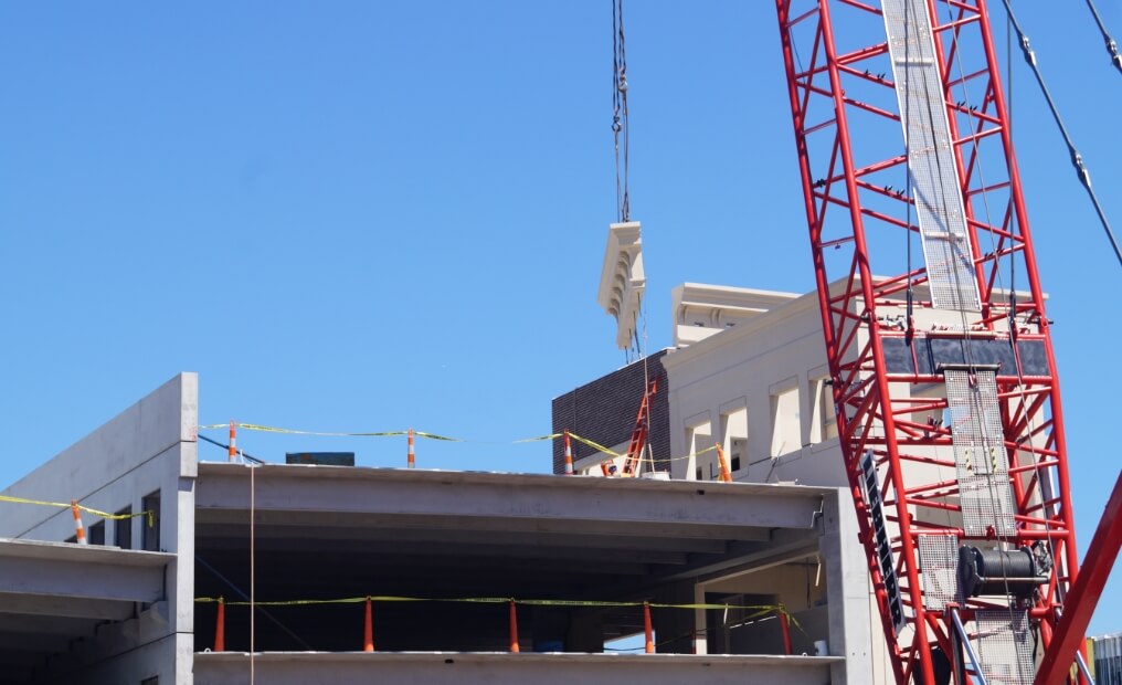 Crane adding precast concrete slab to a building